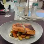 Grilled salmon with vegetables and cocktails on table.
