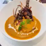 Grilled lobster in creamy curry sauce, garnished with herbs.