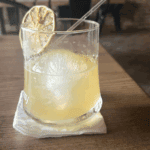 Iced cocktail with a slice of lemon garnish.