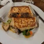 Grilled sandwich with beef filling on white plate.