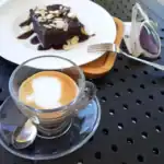 Brownie, almond slices, and coffee on a table.