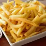 Plate of crispy golden french fries with sauces.