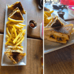 Grilled sandwich with fries on white plate.