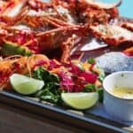 Seafood platter with lobster, lime, and salad on plate.