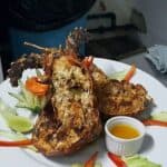 Grilled lobster with vegetables and sauce on plate.