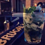 Mint cocktail on bar counter with Brugal logo.