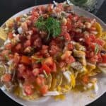 Plate of nachos with tomatoes and onions.