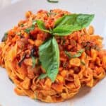 Fresh tagliatelle pasta with tomato sauce and basil.