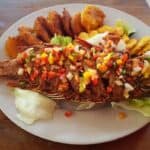 Grilled fish topped with salsa and plantains.