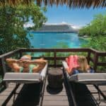 Couple relaxing with cruise ship in background.