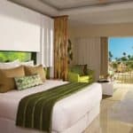 Bright hotel room with balcony and garden view.