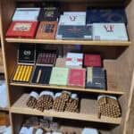 Wooden shelf displaying assorted cigars and cigar boxes.