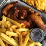 Fried chicken wings and fries in takeout box.