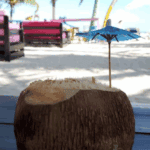 Coconut drink on a tropical beach with umbrella.