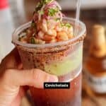 Hand holding shrimp ceviche cocktail with spices