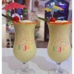Two tropical drinks with umbrellas and cherries