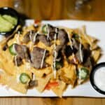 Loaded nachos with steak, cheese, jalapeños, sauces
