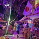 Vibrant night market with colorful clothing and lights.