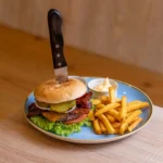 Burger with fries and sauce on a plate.