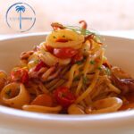 Pasta with calamari and cherry tomatoes in bowl.
