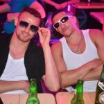 Two men in sunglasses at a bar.