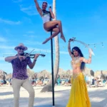 Beach performers: violinist, pole dancer, and belly dancer.