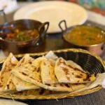 Indian naan bread with curries in copper pots.