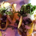 Two beef tacos with onions and cilantro.
