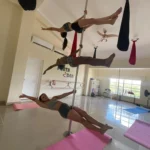 Three women pole dancing in studio.