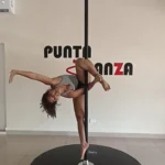 Woman performing pole dance in studio